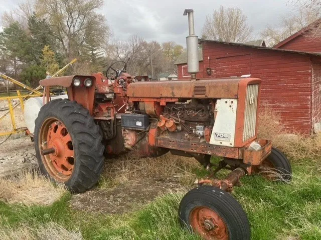 An old, weathered tractor parked by a shed with visible signs of rust and wear.