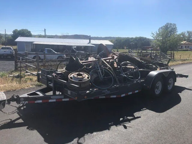 Flatbed trailer loaded with scrap metal and old bicycles.